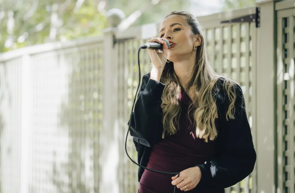 Sally Hall singing live outdoors in a garden courtyard