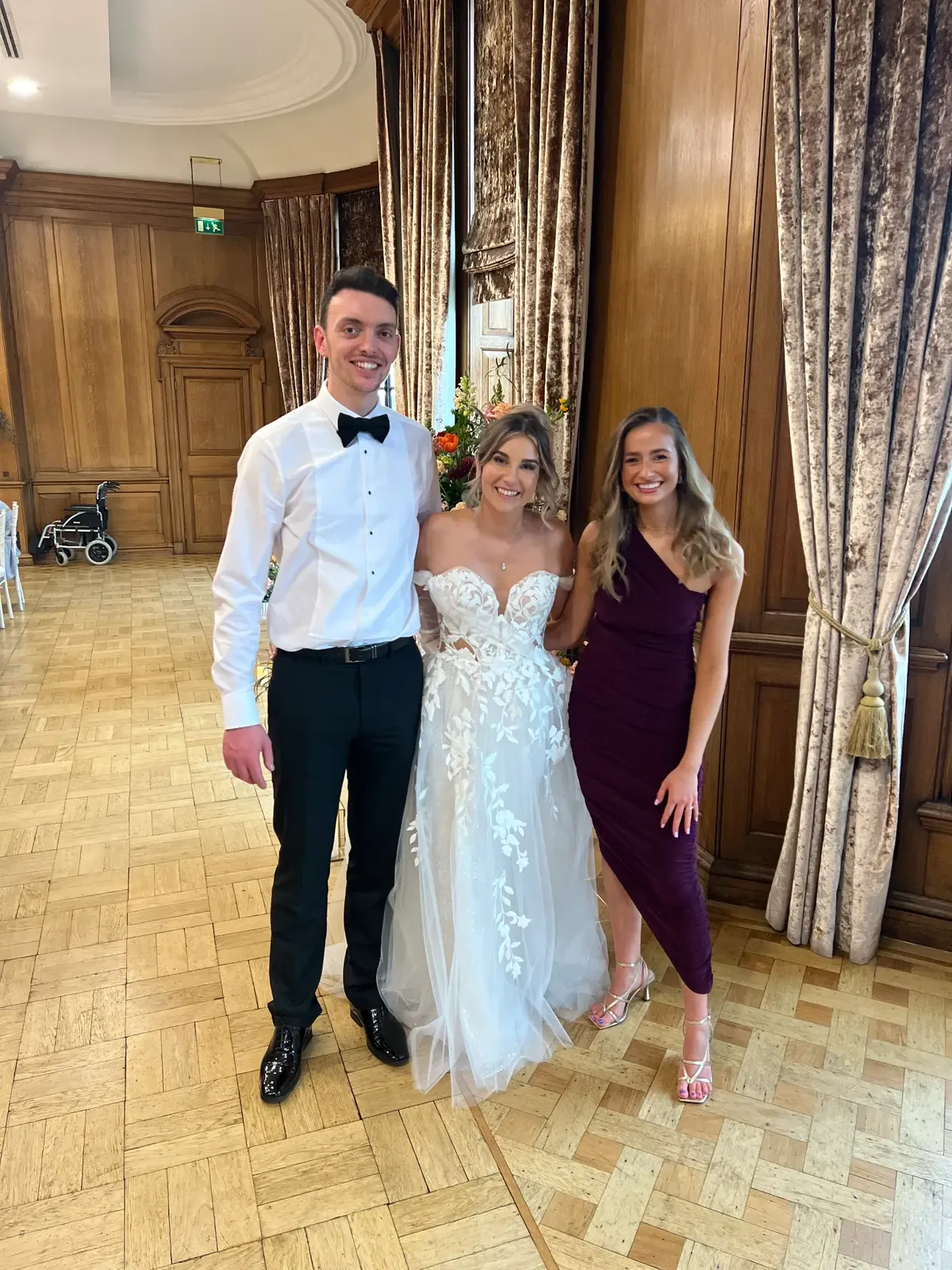 Sally Hall with a newly married couple in an oak-panelled hall
