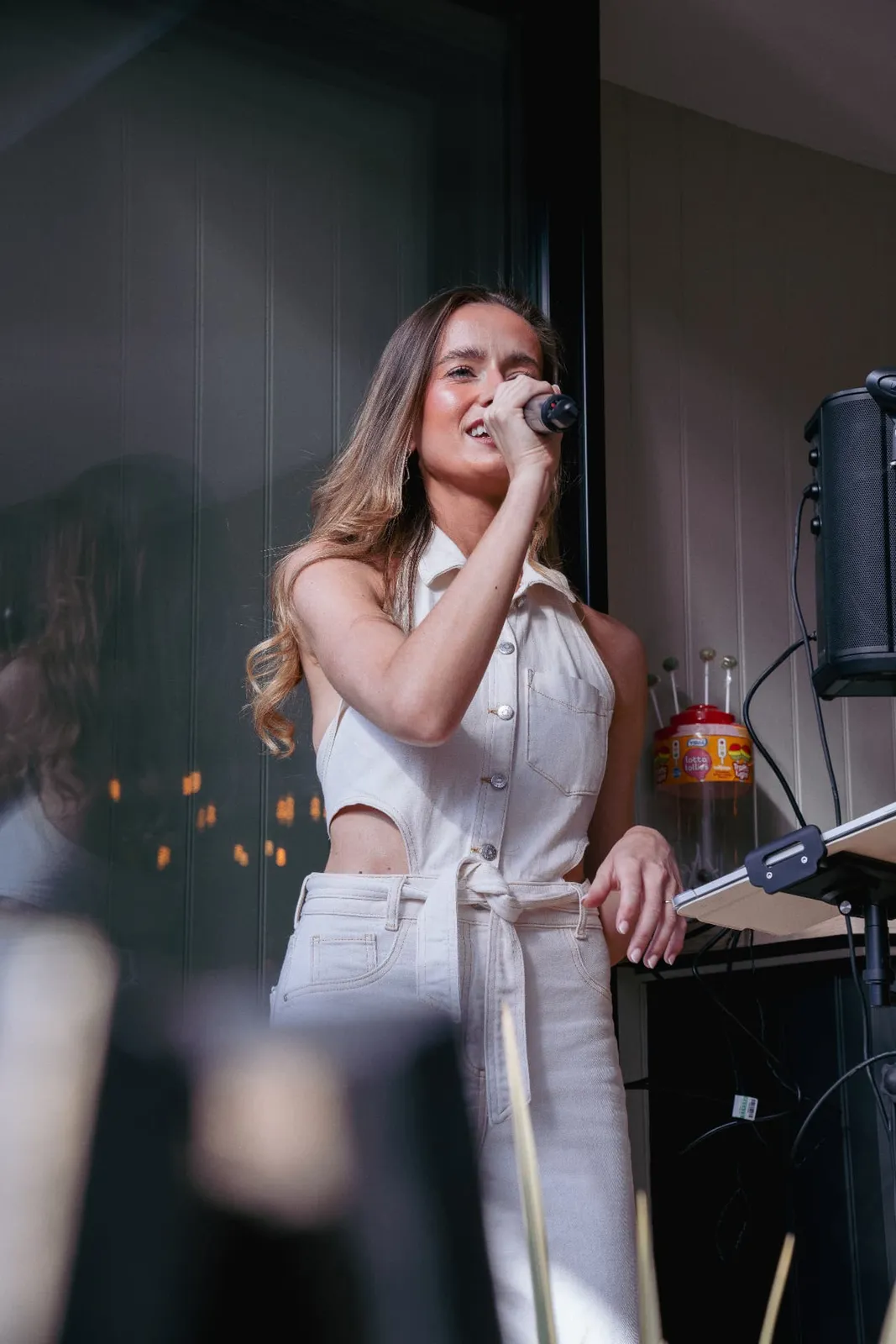 Sally Hall singing into a microphone in a white denim outfit