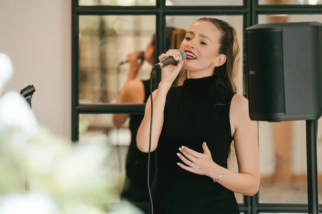 Sally Hall singing in a black dress at an indoor venue