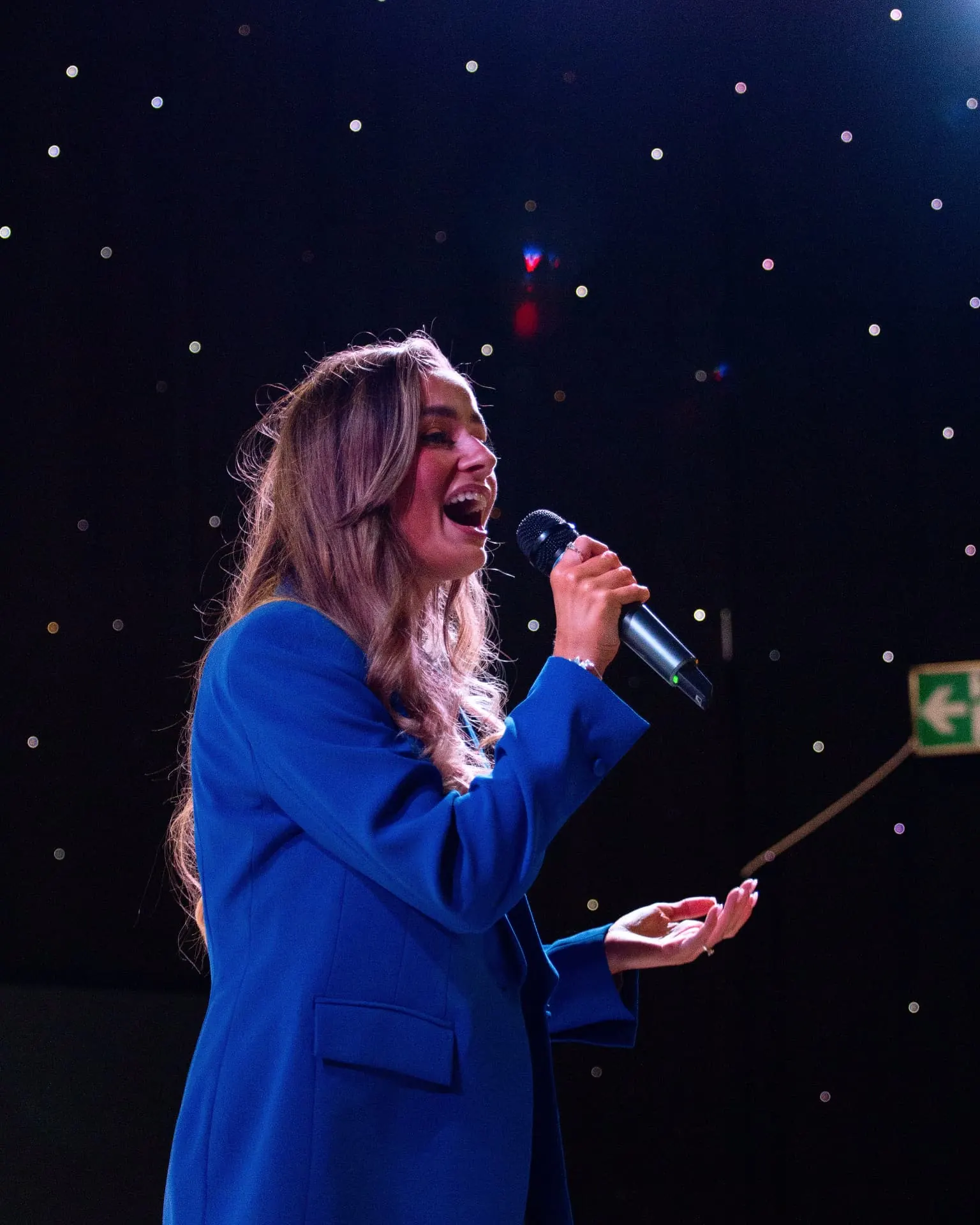 Sally Hall performing on stage in a blue suit